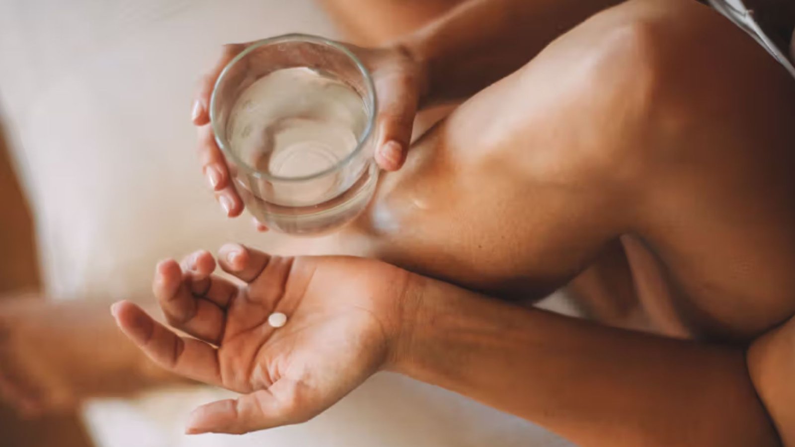 A Woman Holding a Pill in her palm and a Glass of Water 